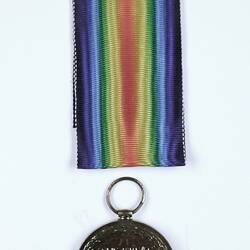 Round medal with text and rainbow coloured ribbon.