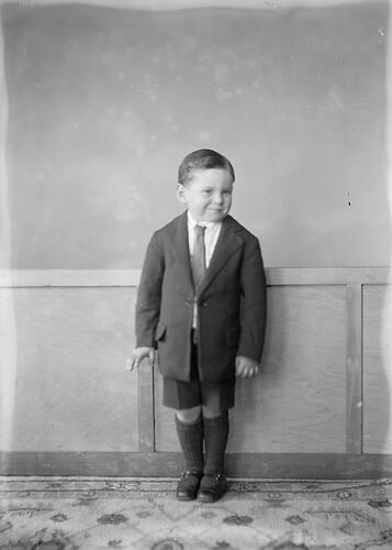 Boy in jacket, tie and shorts.