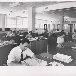 Men and women working in open plan office.