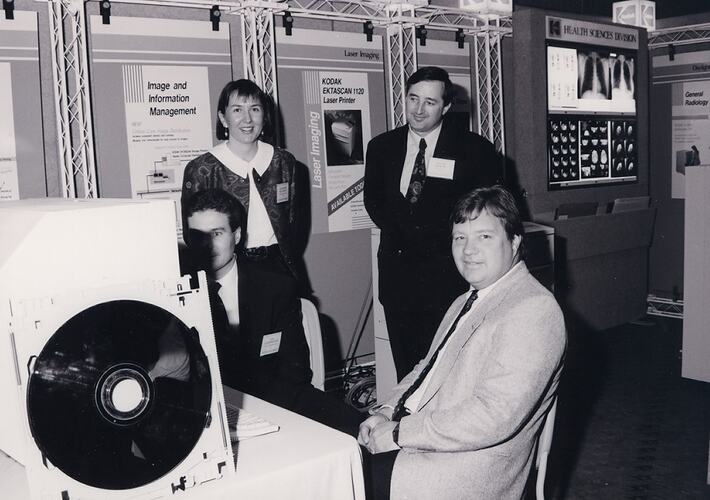 Four people at computer inside x-ray product display.