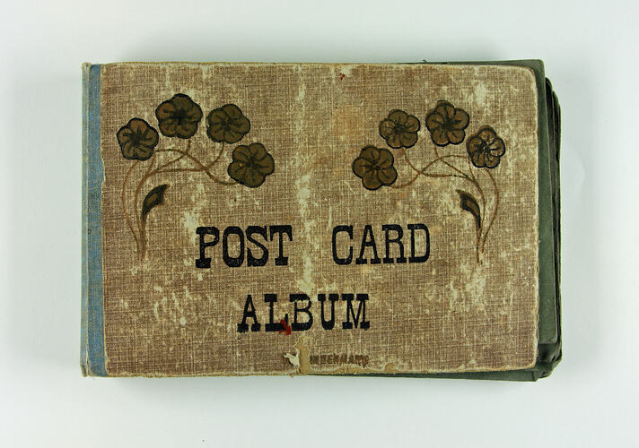 Cover of postcard album with brown poppies and writing.