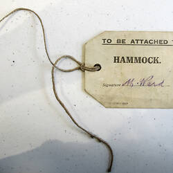 Label with printing and hand-writing, string attached.