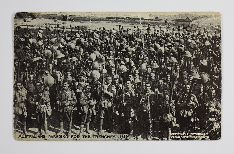 Australian soldiers holding their helmets high.