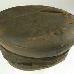 Three-quarter overhead view of old battered nightsoil collector's khaki flat top cap