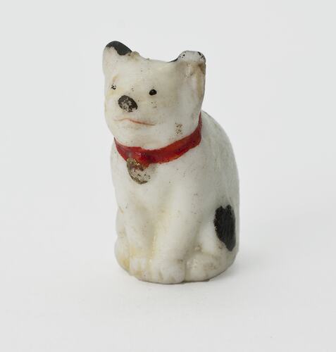 White cat figurine. Black spots and red collar.