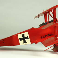 Red aeroplane model. White strip on top of wings with black cross. Right profile.