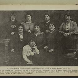 Eight women pose. Four stand behind three seated women whilst one woman kneels at front. Printed names below.