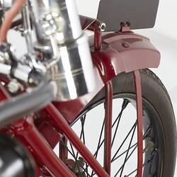 Red motor cycle, red front fender with blank metal tag on top detail. Right side.