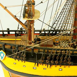 Detail of rear of deck on model ship with wooden hull painted yellow.
