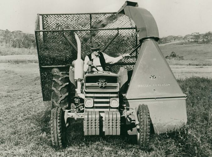 Man driving a tractor fited with a forage harvester. Storage cage being filled.