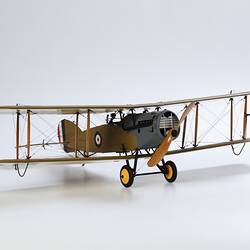 Model biplane aeroplane painted mustard brown with grey engine. Three quarter right view.