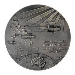 Dull silver round medal with three bi-planes flying above a globe depicting Australia.