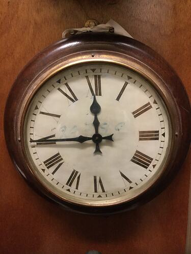 Round clock with wood and metal frame. White face and roman numerals.
