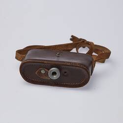 Brown leather camera case with strap. Metal ring at base.