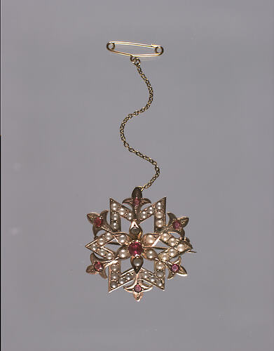 Gold and garnet brooch with chain above.