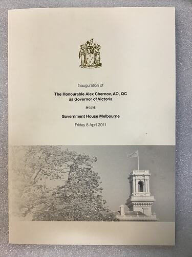 Programme cover, white with black printed text. Coat of arms above. Treetop and building tower with flag below