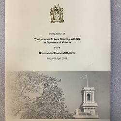 Programme cover, white with black printed text. Coat of arms above. Treetop and building tower with flag below