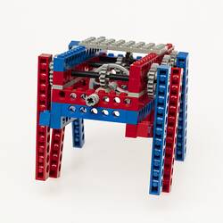 Red, blue and grey LEGO robot with three legs either side. Back.