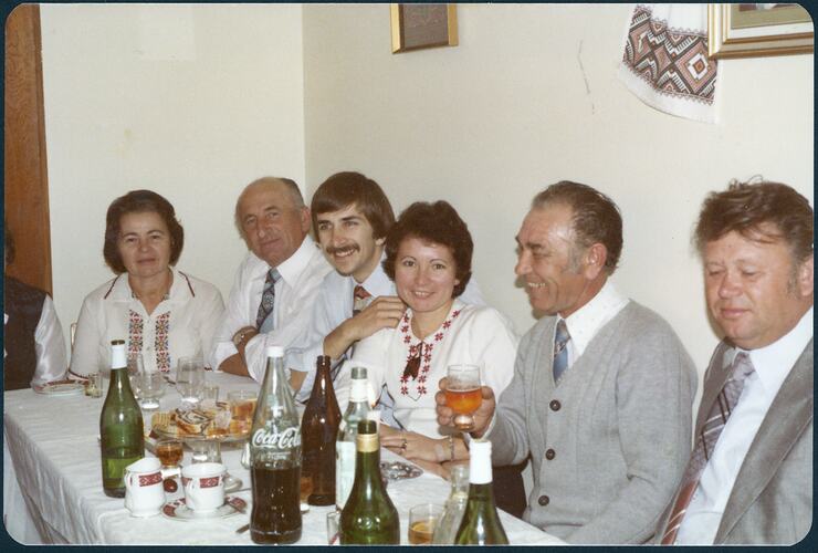 Six adults seated at table celebrating a christmas family gathering.