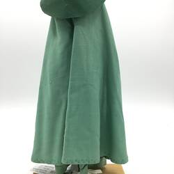 A doll dressed in a long green gown, veil and hat