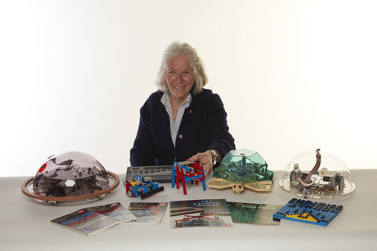 Woman sitting at table with lego robotic items and booklets.