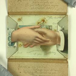 Open birthday card with a four flap design. Opens horizontally. Has male and female holding hands, Pale flowers behind. Text above and below.