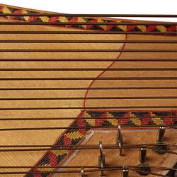 Detail of section of timber stringed instrument. Pale wood with black laquered timber detail. Multi stringed.