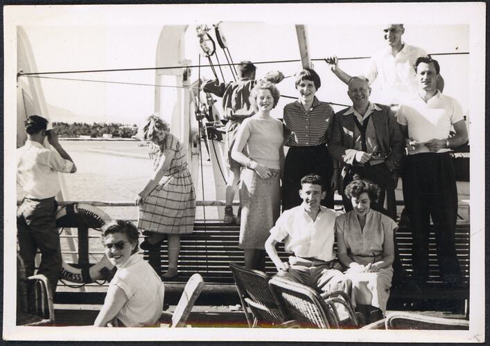 Group posing in front of a lifeboat onboard a ship.