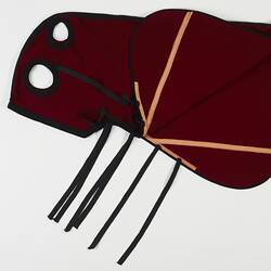 Red and black woollen horse hood. Four straps. Two cut out holes.