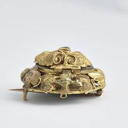 Round gold brooch with gold border and green paste. Profile view.