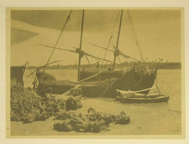 traditional sail boats anchored on shore.