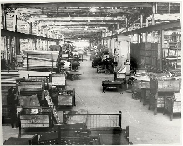 Factory interior with wheeled trolley, metal racks and shelving.