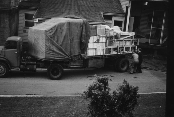 Fully laden truck attended by two men.