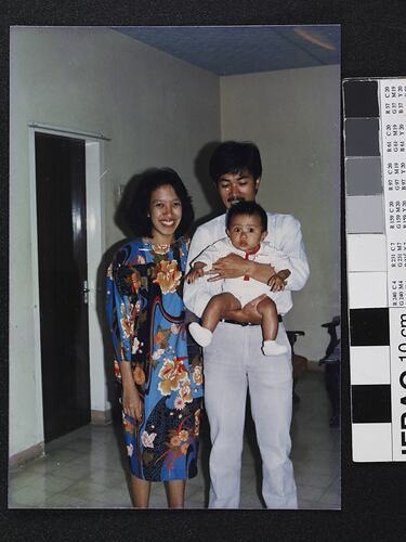 Woman and man smiling as he holds a baby.