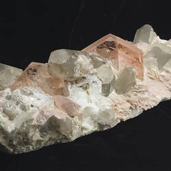 Grey-white rock with pink crystals on one surface.