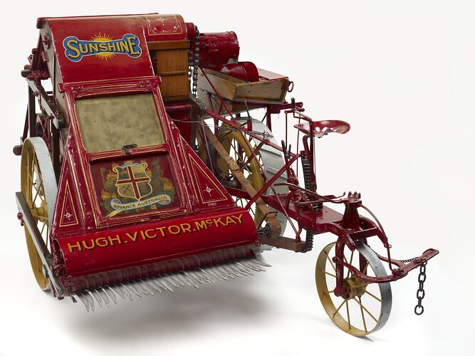 Model of red stripper harvester with yellow lettering.