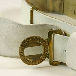 Detail of white belt showing brass buckle.