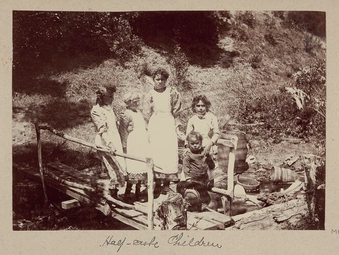 Five children standing on a small wooden footbridge.