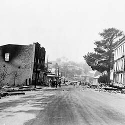 Fire damaged street with ruined buildings either side.