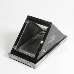 Triangular glass roofed container with black hinged metal frame on base. Text printed on black metal side.