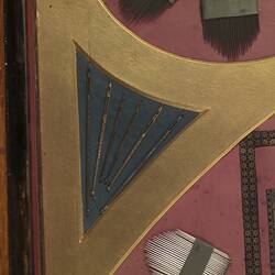 Detail of panel made of needles, crochet hooks, surgical needles, and other needles and needle cases. In red, black and yellow.