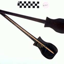 Two part black wooden case with long thin arm and bulbous end. Used to house ivory and brass scales.