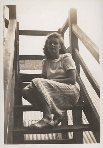 Woman seated on timber stairs.