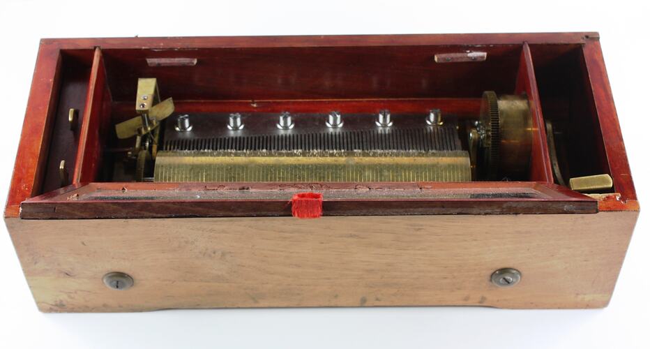 Mechanical music box with lid open, showing workings.