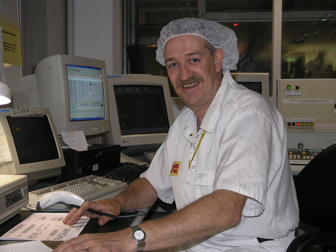 Man in hairnet at computer station.