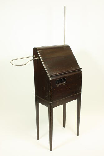 Front angle view of theremin in wooden case on four legs.