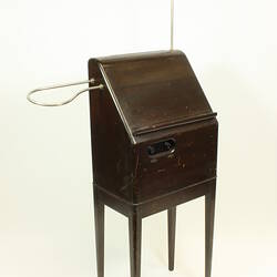 Front angle view of theremin in wooden case on four legs.