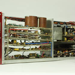 Red control panel with knobs and dials on front of metal box. Case removed to show internal wires and components.