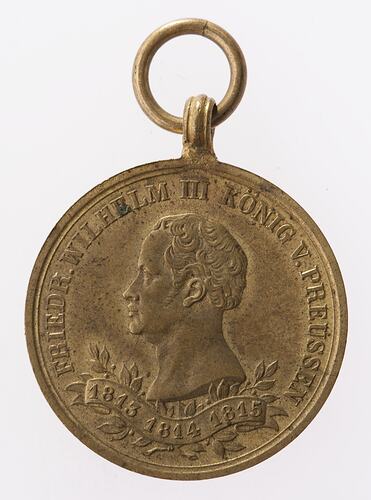 Round medal with male profile facing left. Suspension ring at top. Text around.