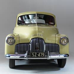 Cream holden car, front view of polished chrome grille and bumper.